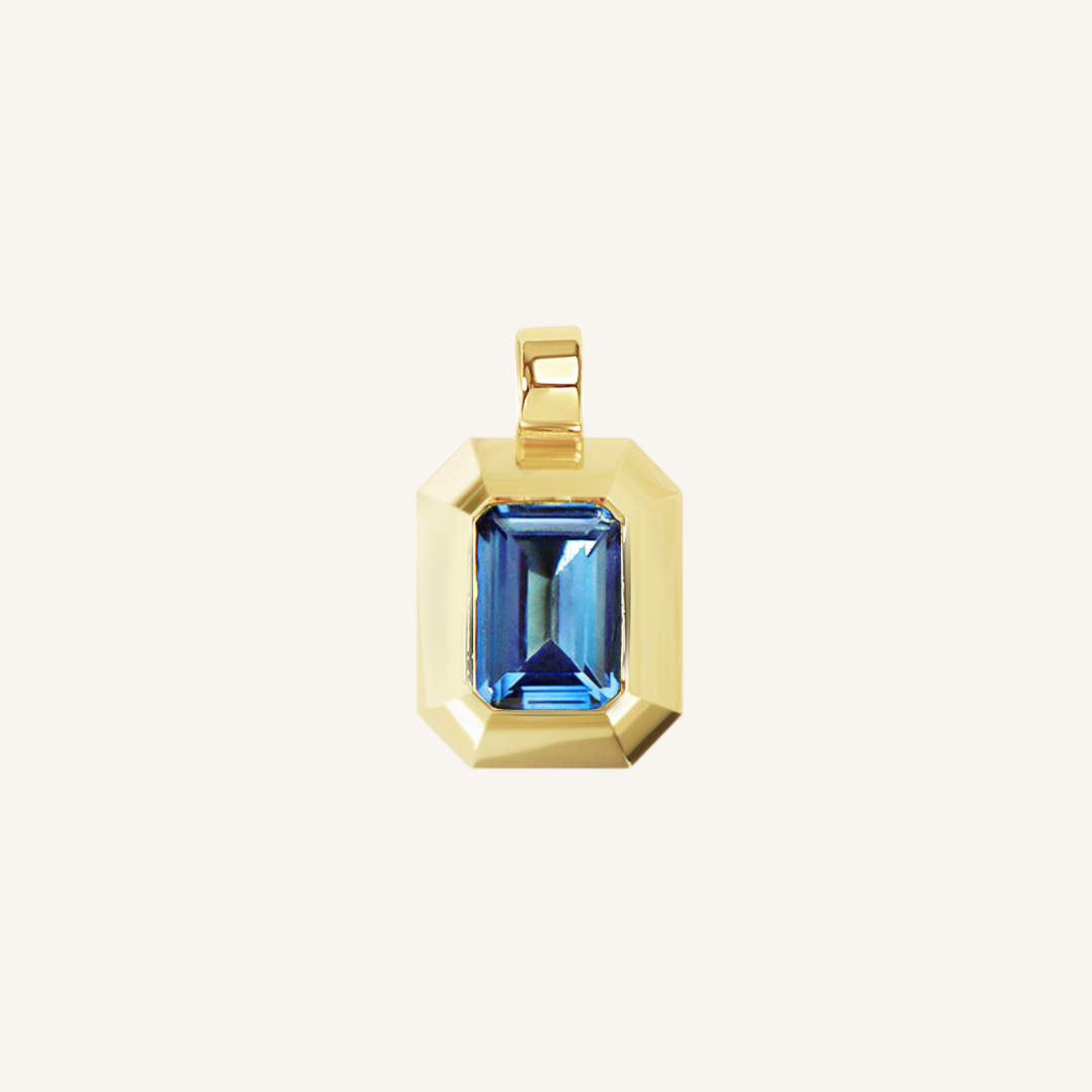 Gold charm with Blue emerald cut cubic zirconia bezel set Inspired by the halls of Versailles on white background