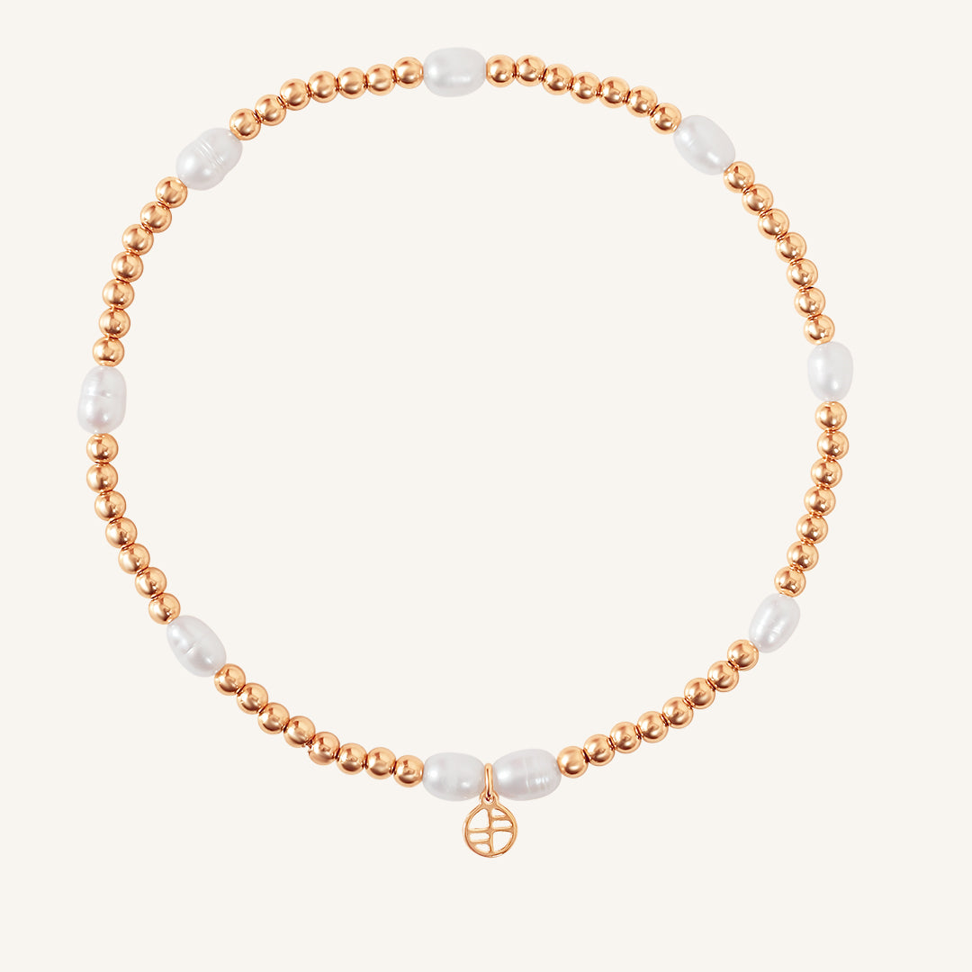 A coloured stretchy anklet with freshwater pearls and a small gold charm, displayed against a white background.