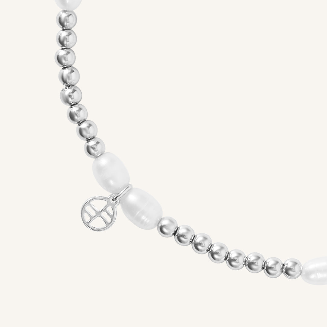 A coloured stretchy anklet with freshwater pearls and a small gold charm, displayed against a white background.