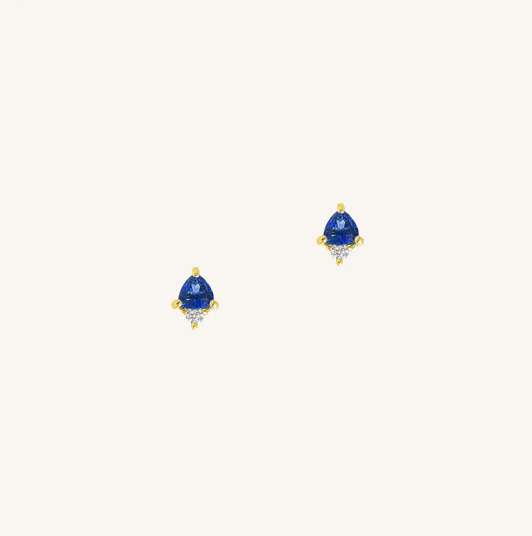 A gold pair of stud earrings featuring a blue cubic zirconia, representing September.