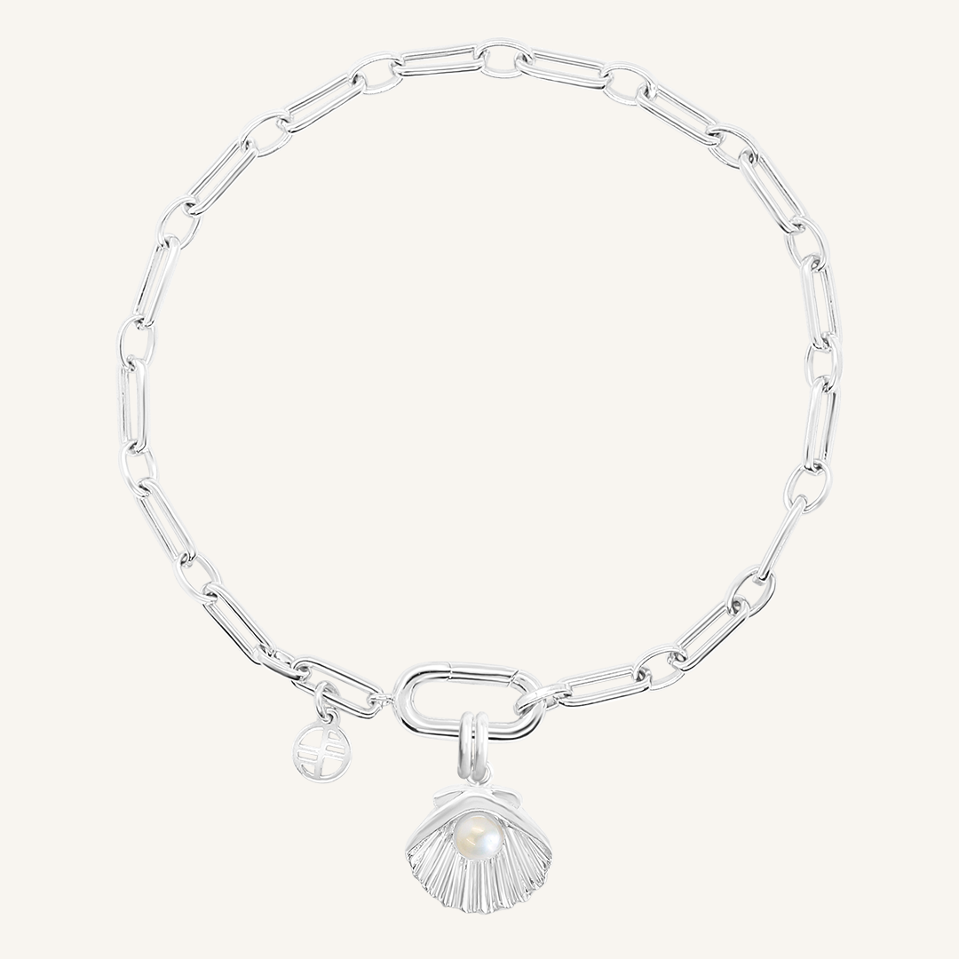 A silver-colored chain bracelet with a shell shaped charm with a pearl in the middle