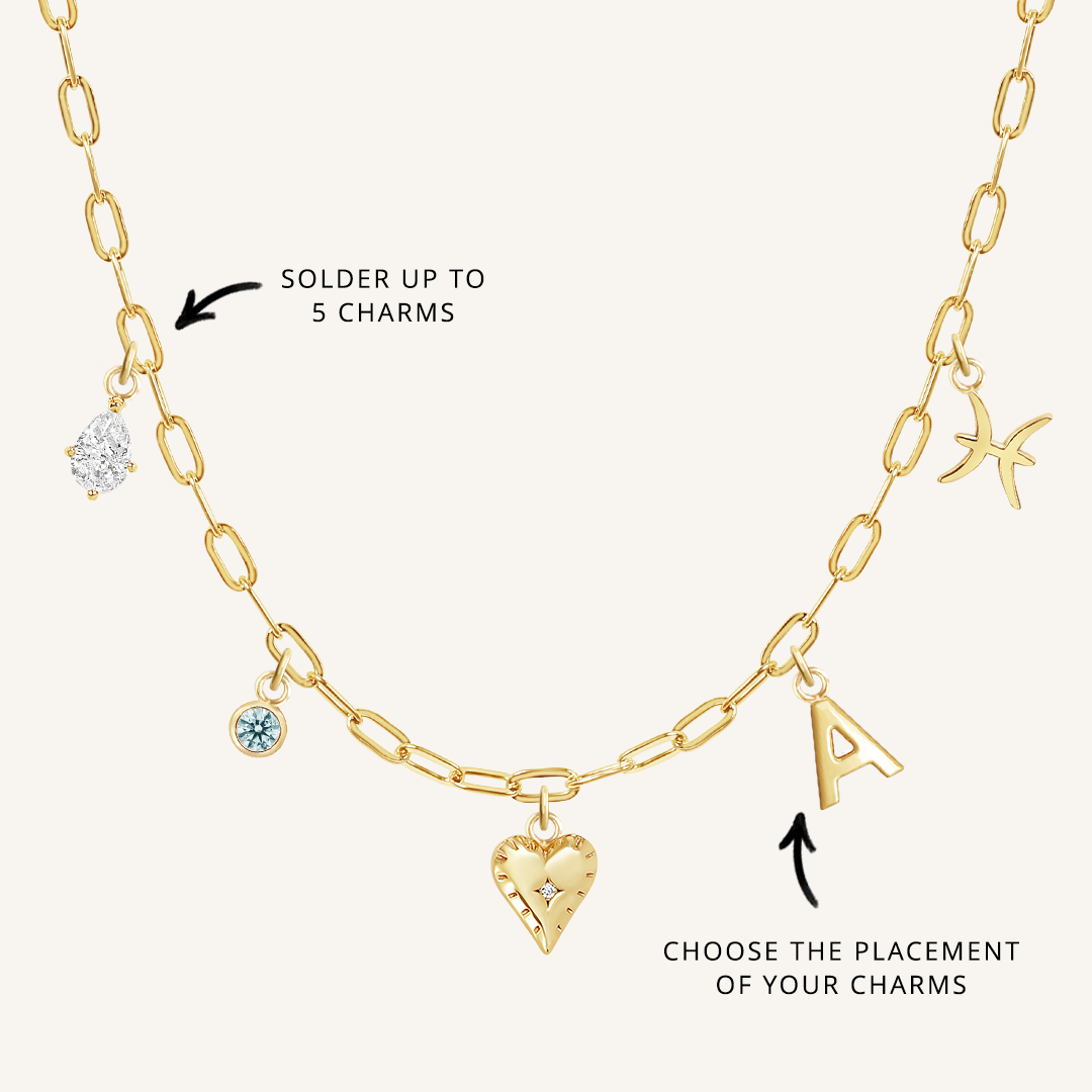 A gold chain necklace with paperclip links and multiple charms, showcasing where to solder charms and the option to choose the placement of the charms.
