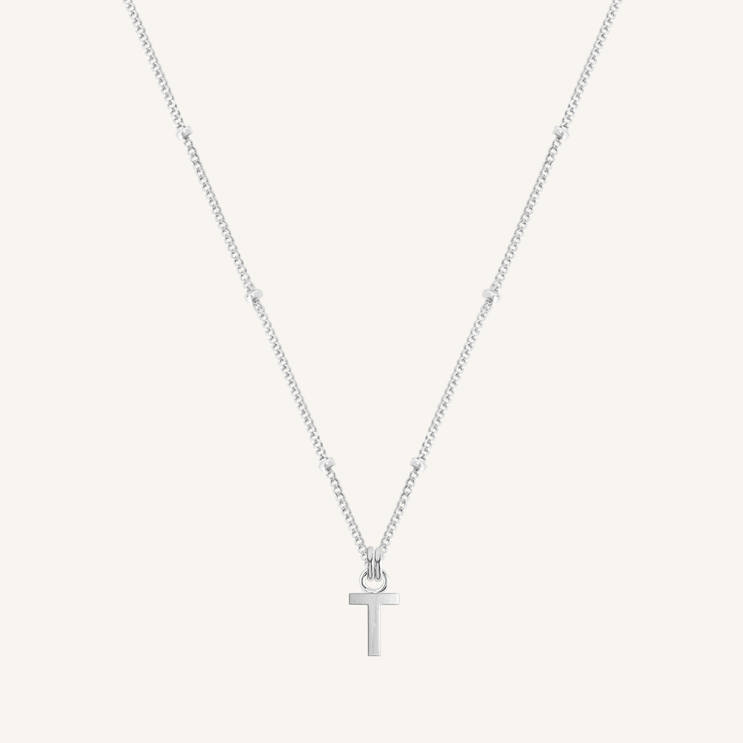 Silver necklace with a 'T' pendant on a light gray background
