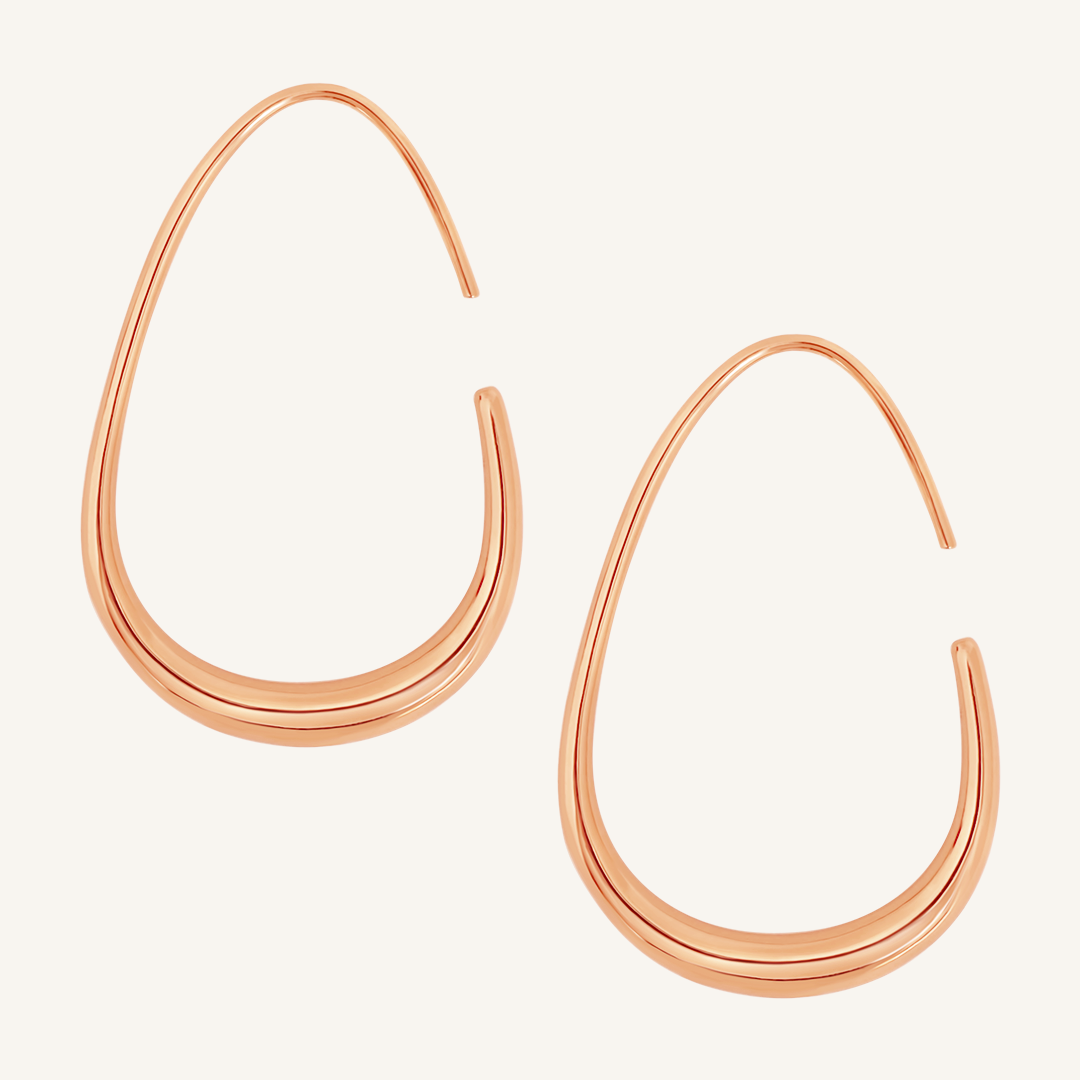 A pair of rose-colored hoop earrings with a geometric design, displayed against a white background