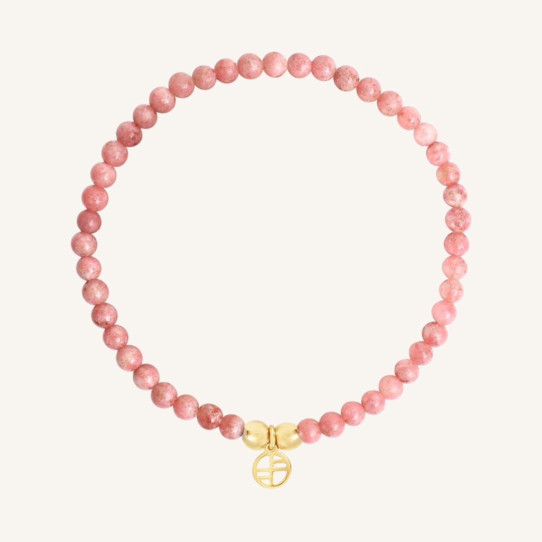 Pink beaded bracelet with a gold charm on a white background