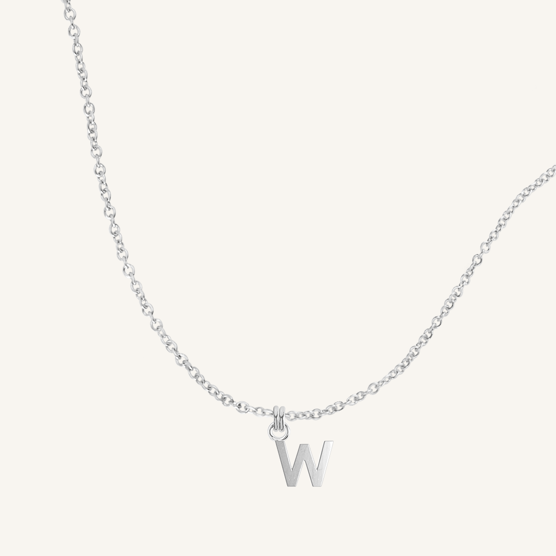 Silver necklace with a 'W' pendant on a light gray background