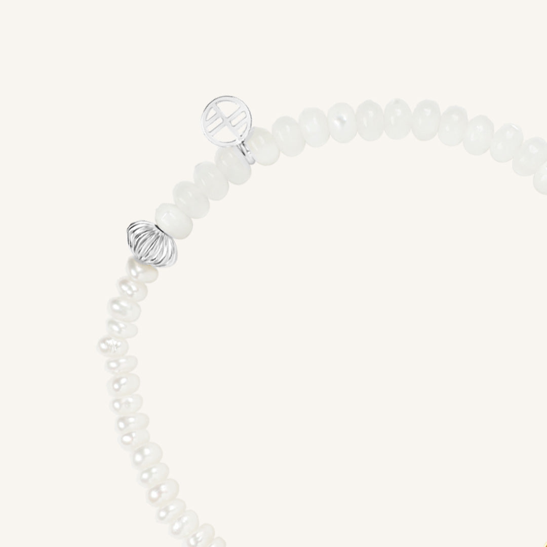 Bracelet with white beads and silver wire-like elements on a white background