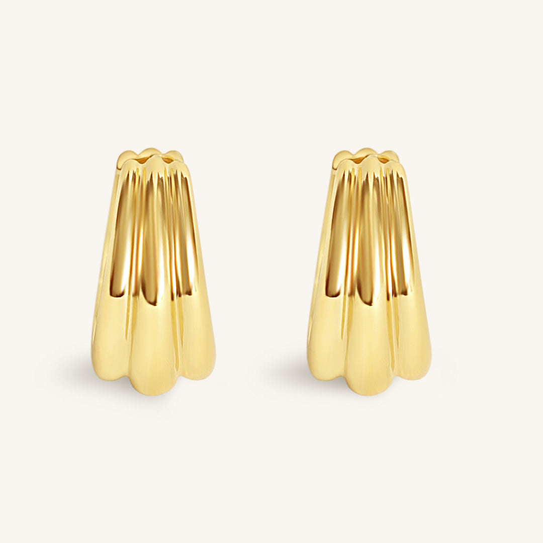 Gold earrings on a light beige background