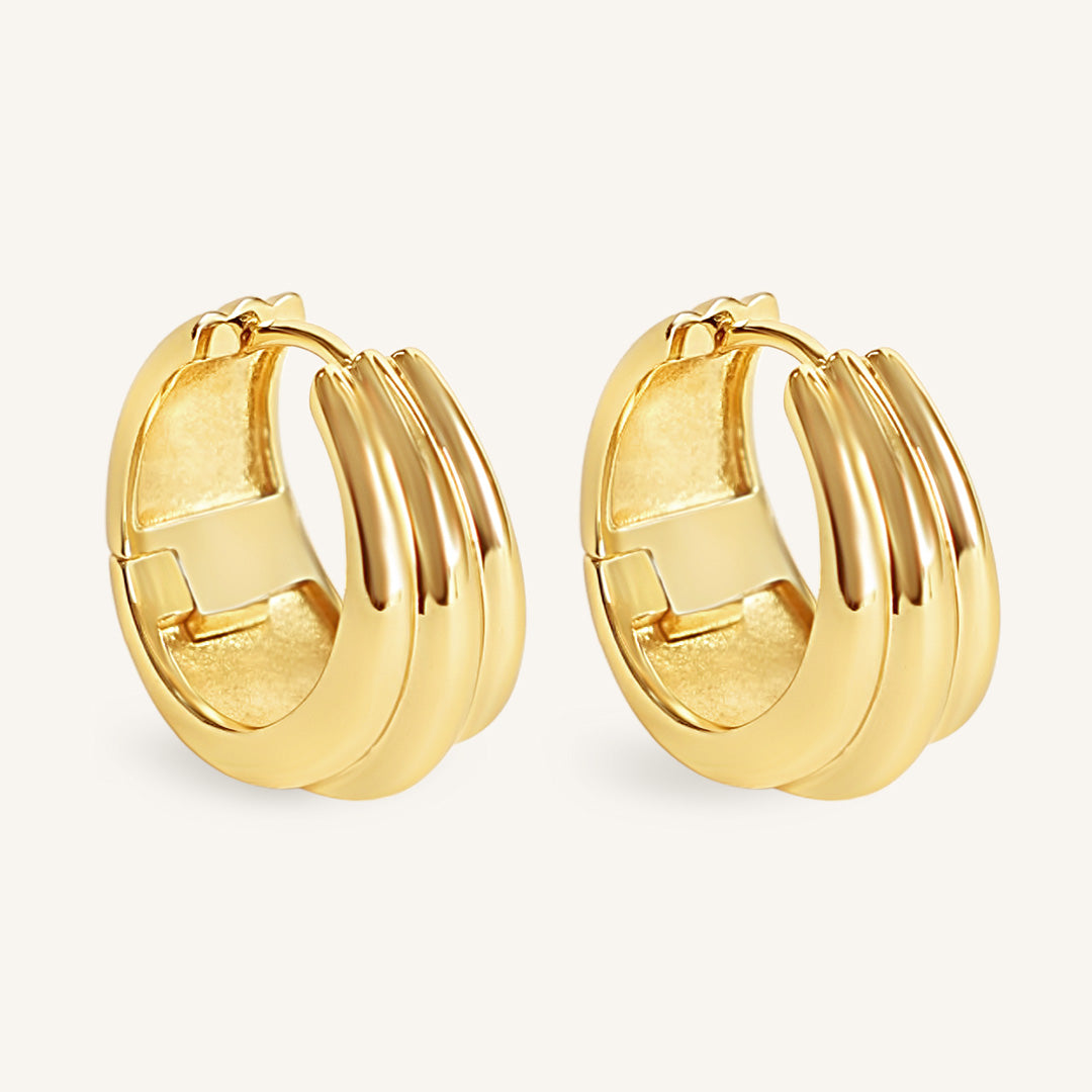 Pair of gold hoop earrings on a light beige background