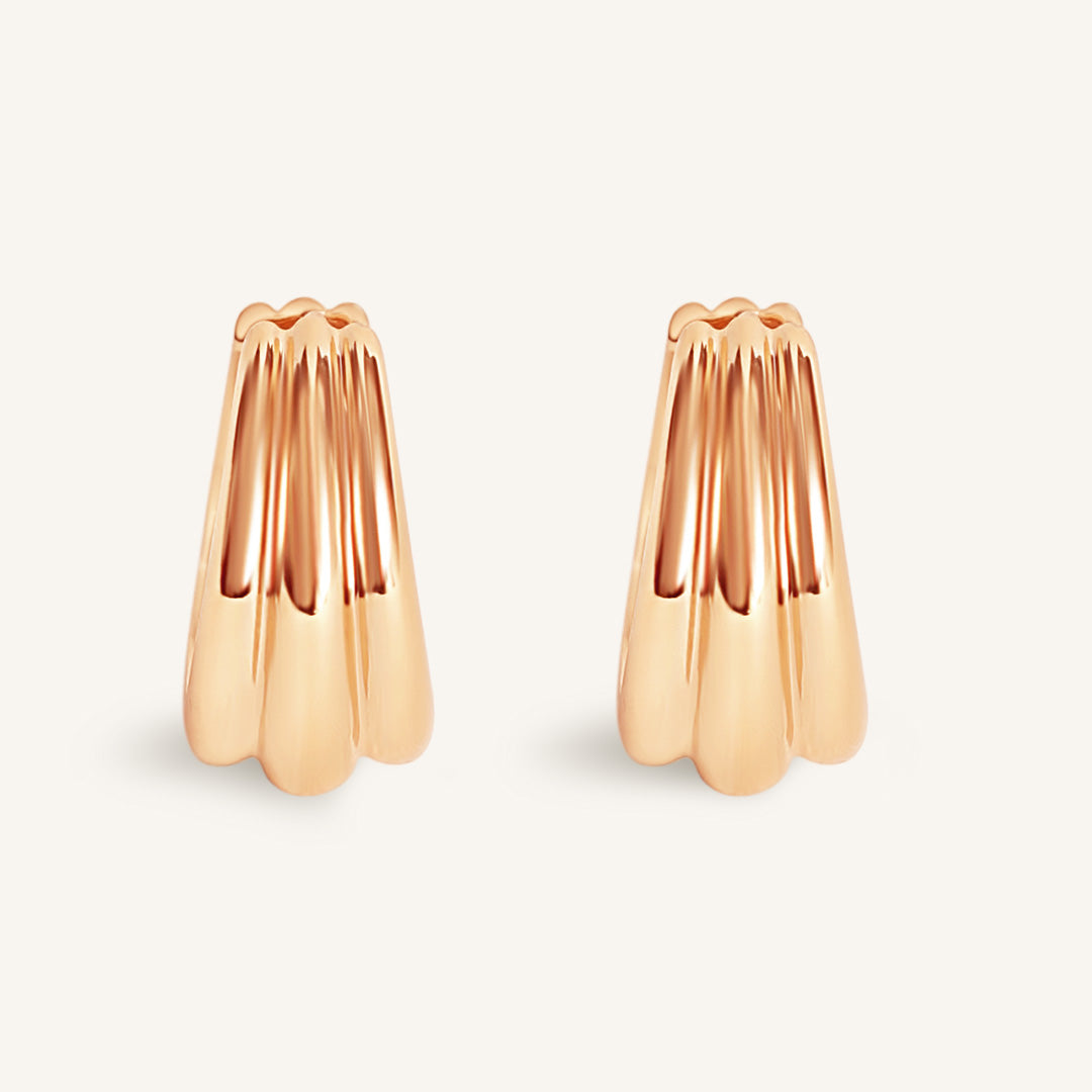Rose gold earrings on a light beige background