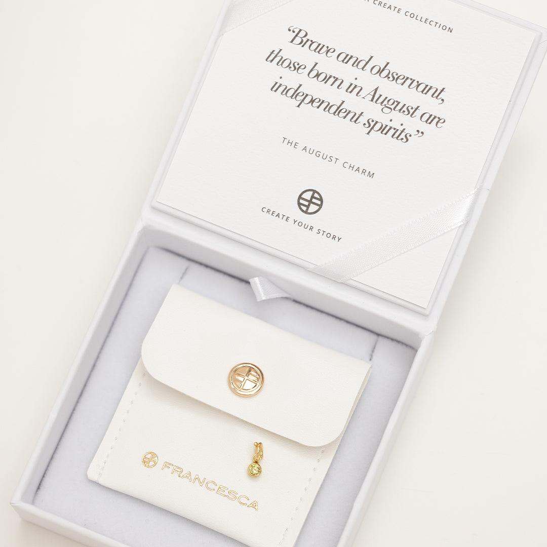 Gold round charm with bezel-set peridot green cubic zirconia representing the August birthstone in white box