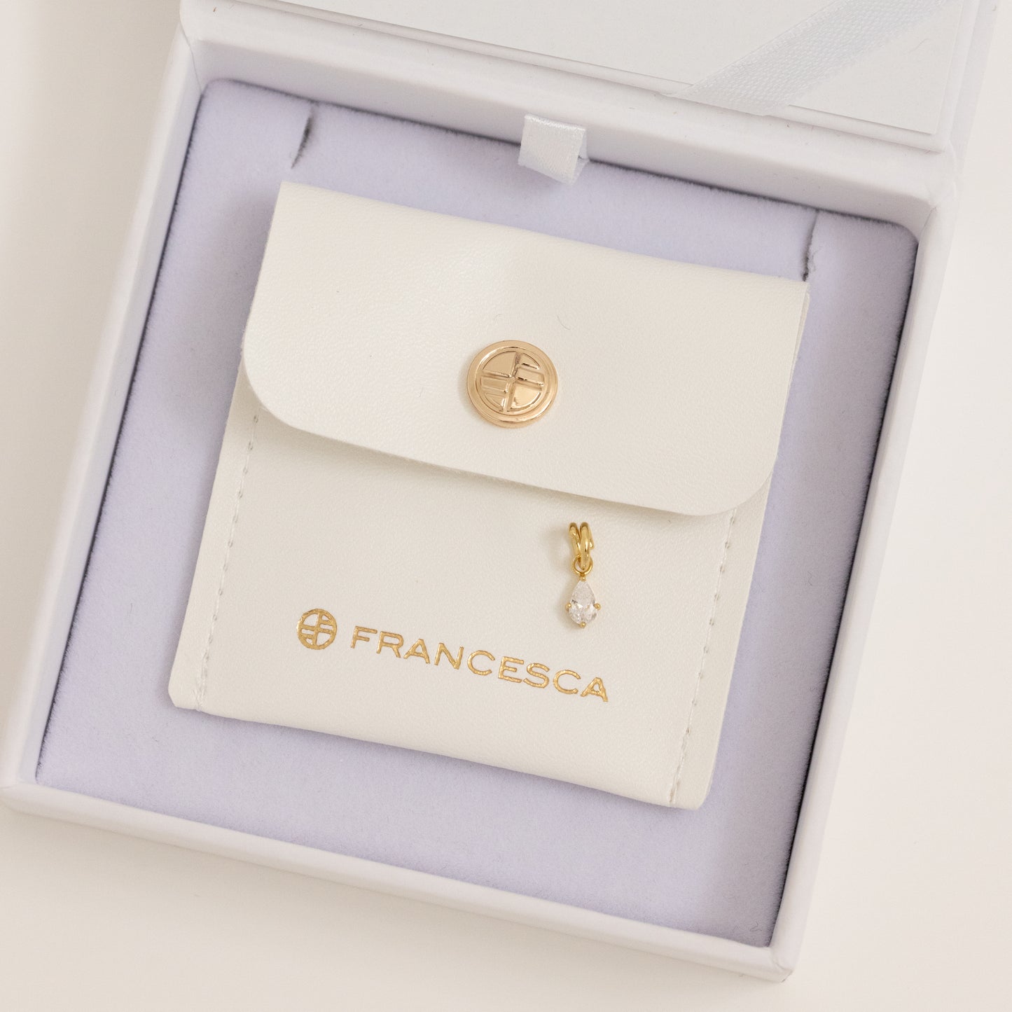 A teardrop-shaped cubic zirconia charm with a gold metal tone, in white box