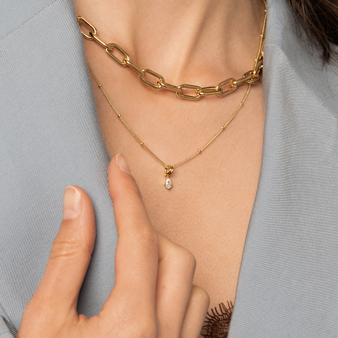 A chunky link chain necklace in gold tone worn on models neck