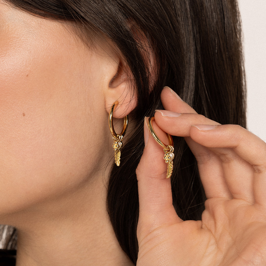 A set of two hoop charm earrings, featuring petite bobble details, attached to hoops, worn by model