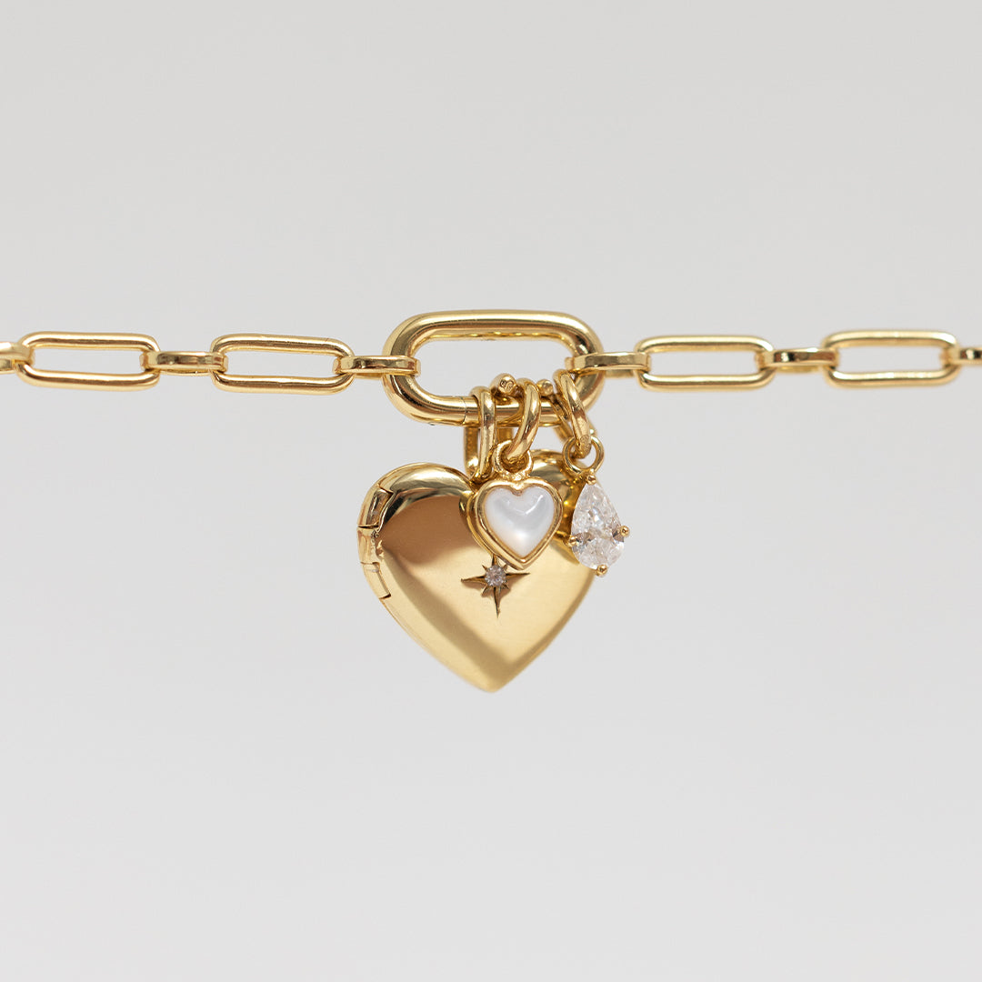 A teardrop-shaped cubic zirconia charm with a gold metal tone, on gold link chain
