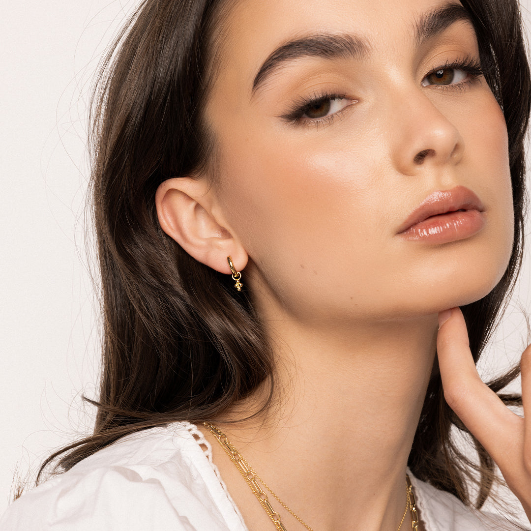 A set of two hoop charm earrings, featuring petite bobble details, attached to hoops, worn by model
