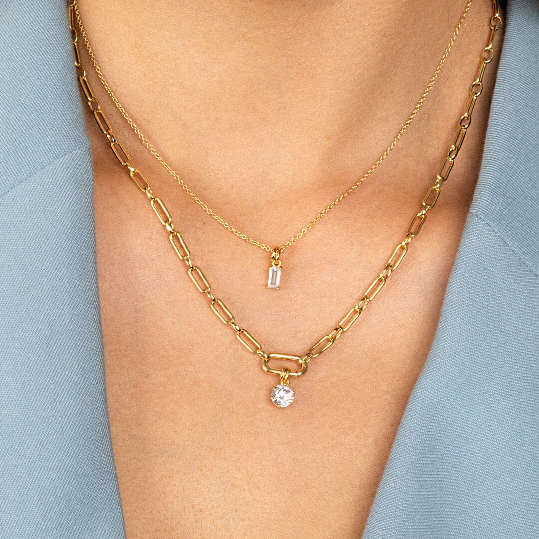 A round gold cubic zirconia charm on link chain, worn on neck