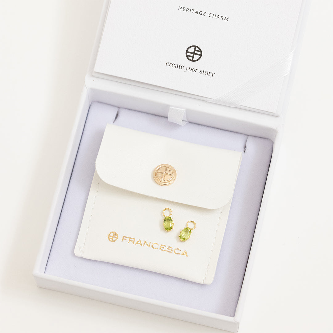 A set of two gold hoop charms with olive green stones, isolated in white box.