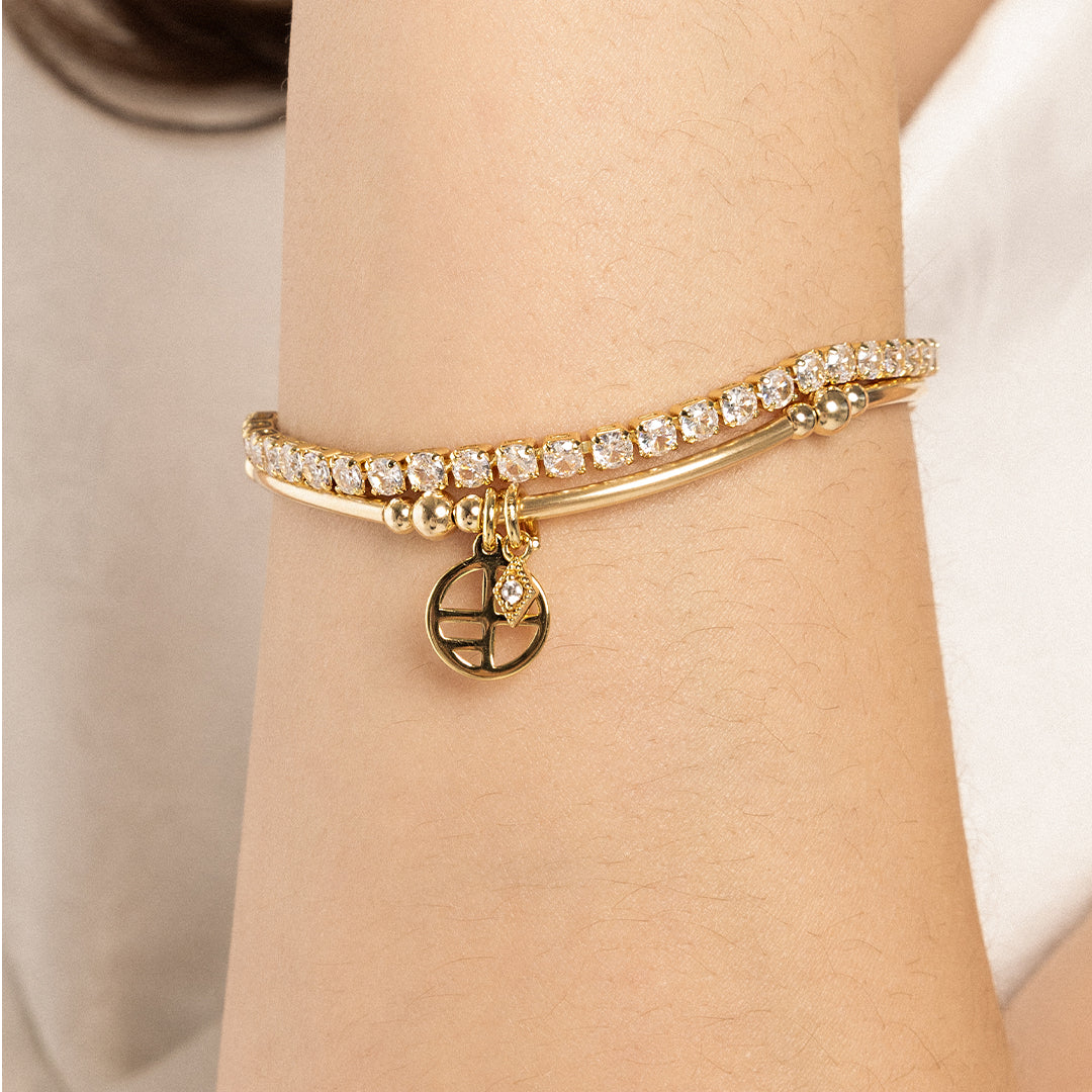 A gold-tone charm bracelet with a petite diamond charm and a stretchy bead chain, on wrist