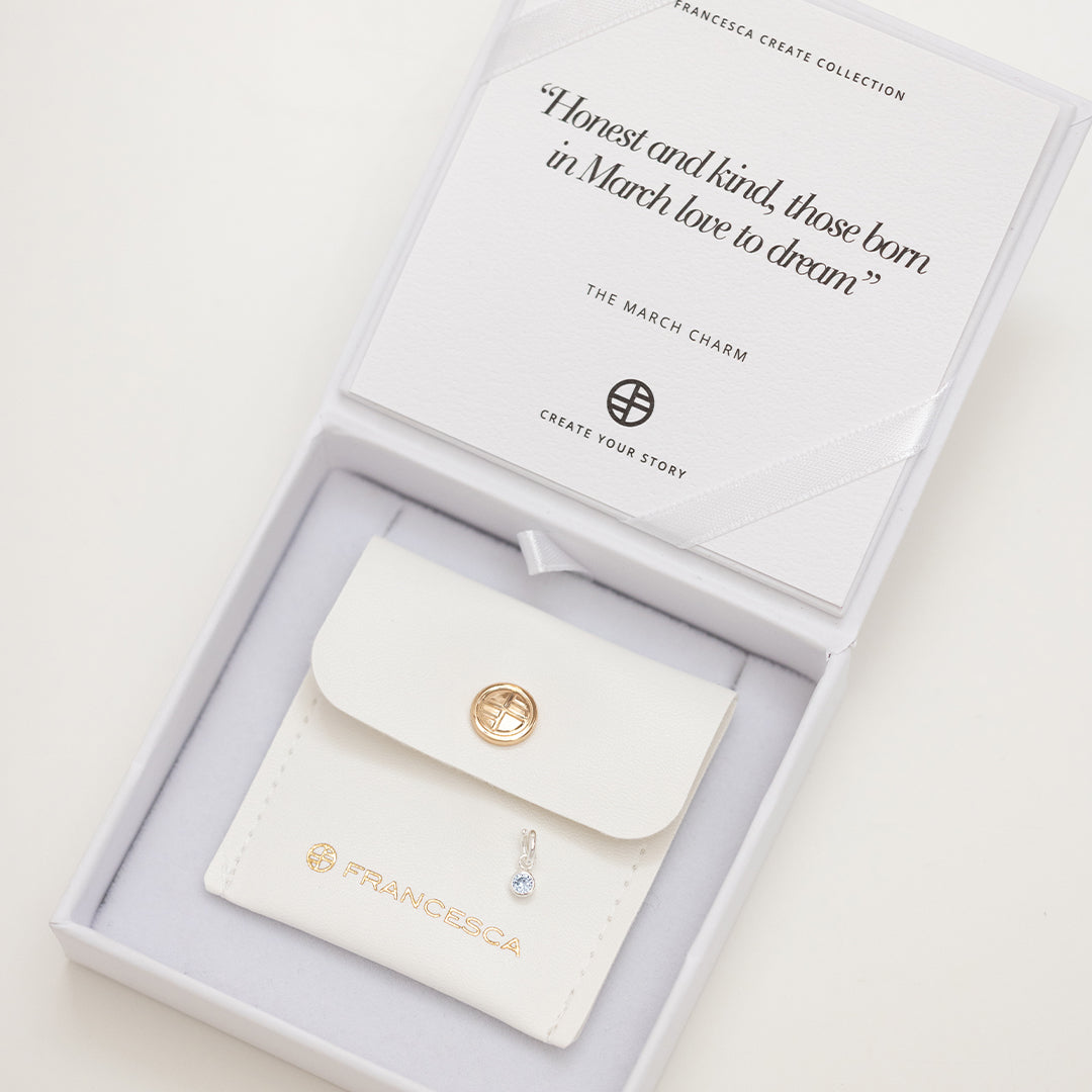 Round gold charm with bezel-set aquamarine cubic zirconia representing the March birthstone in white box.