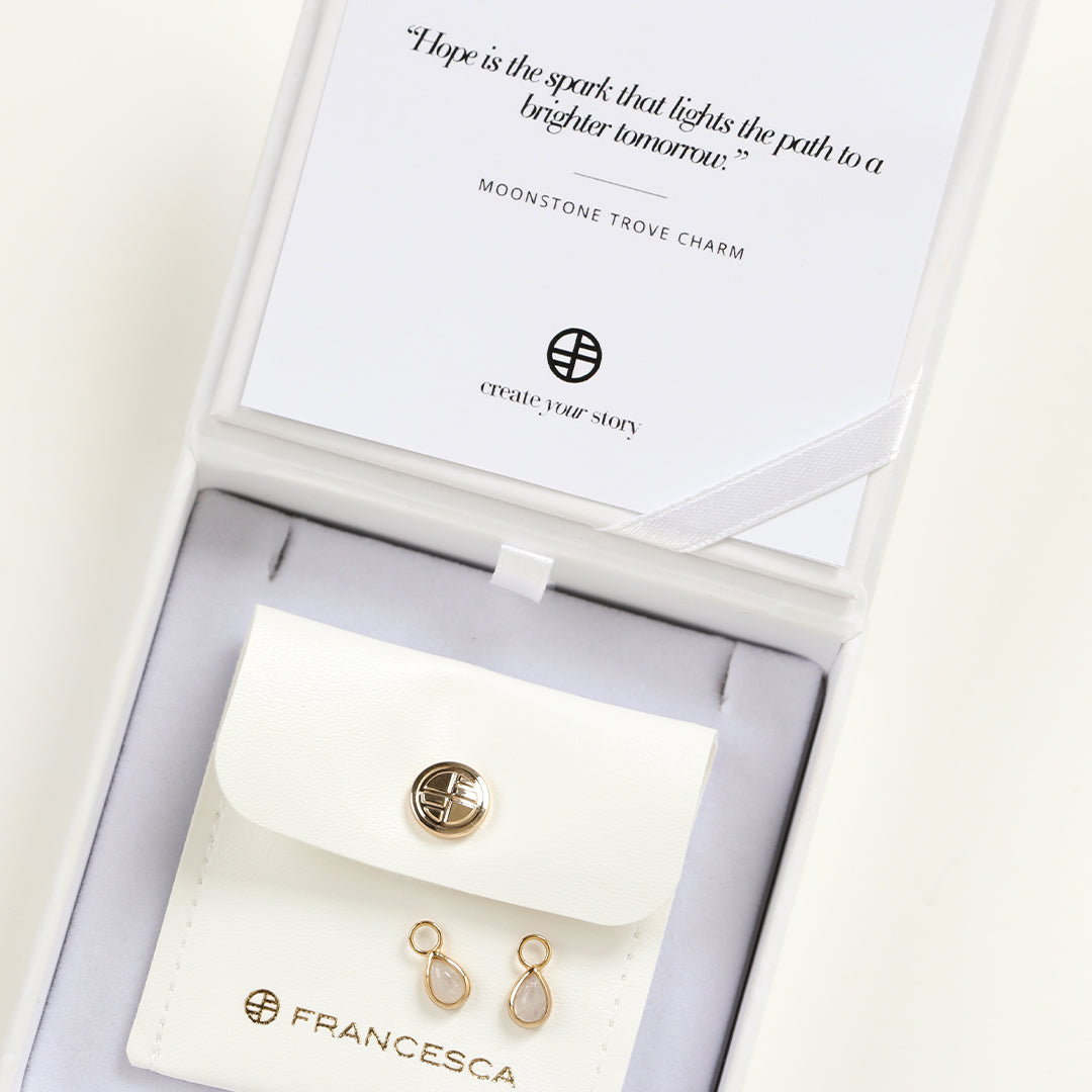 A set of two gold hoop charms with teardrop-shaped Moonstone stones in white box