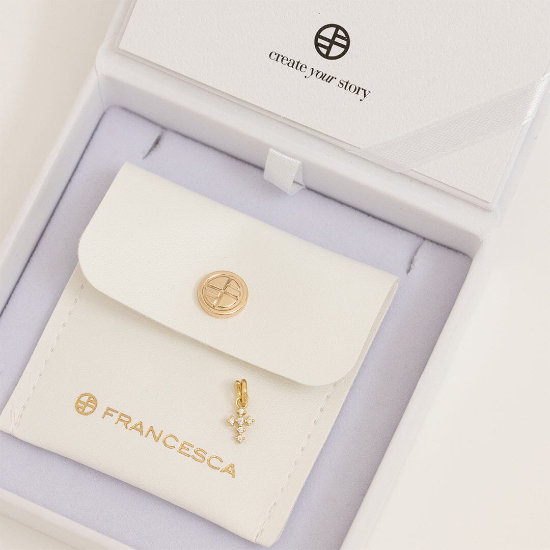 A petite gold cross charm with cubic zirconia in white box