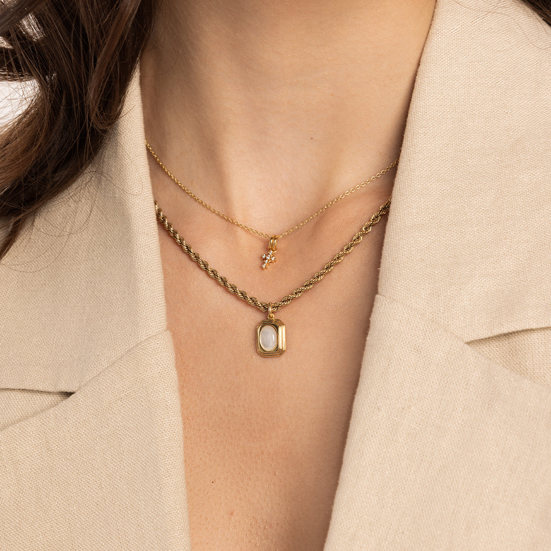 A gold-tone Nurture Cross Charm Pendant Necklace with a vintage cross shape on a chain, around neck