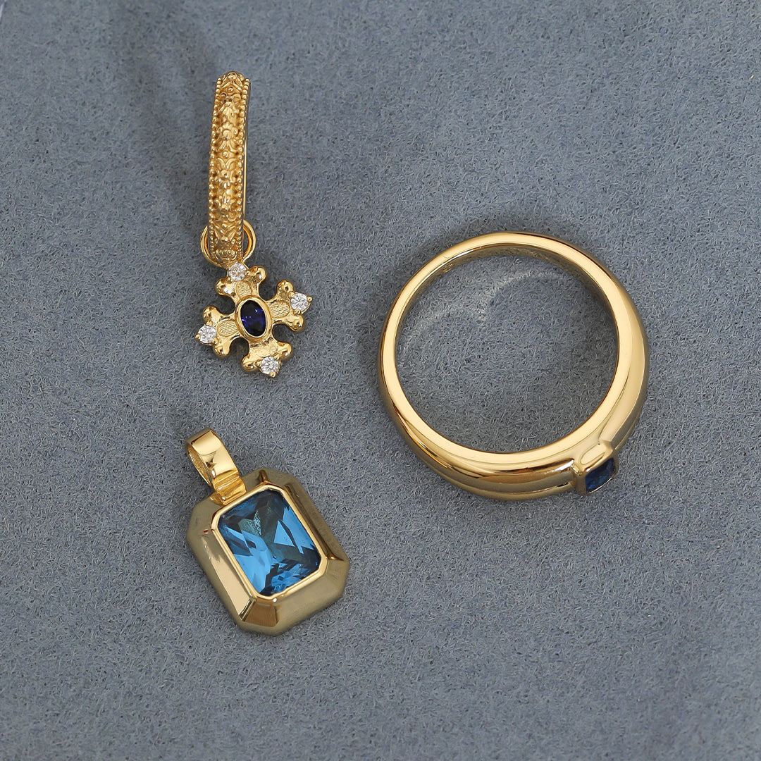Gold charm, hoop and ring with Blue emerald cut cubic zirconia bezel set Inspired by the halls of Versailles on blue background
