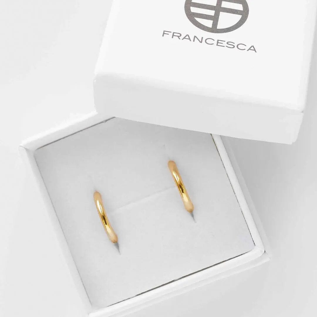 A pair of gold-colored hoop earrings in white box