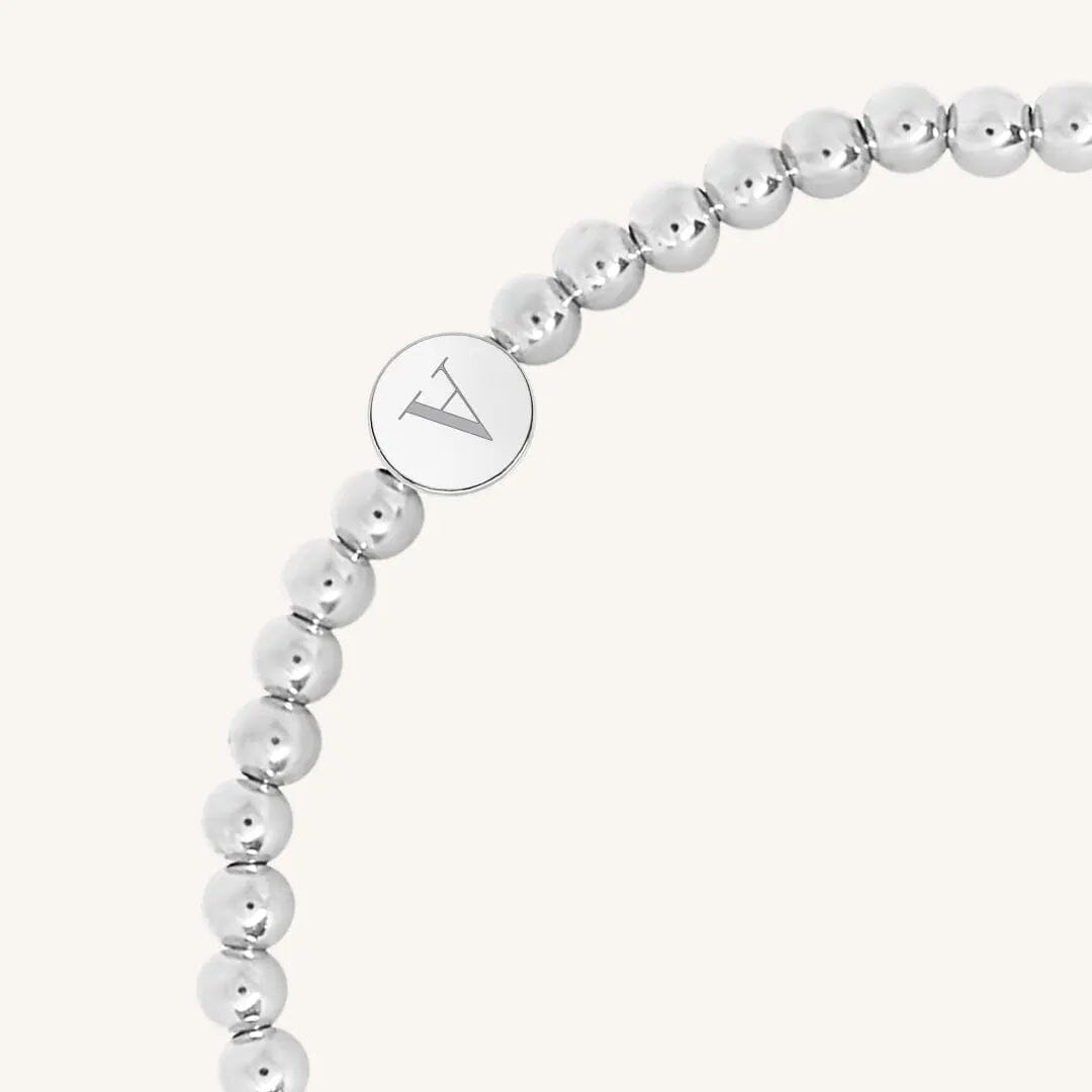 A silver bracelet with a beaded design and an engraveable bead, close up