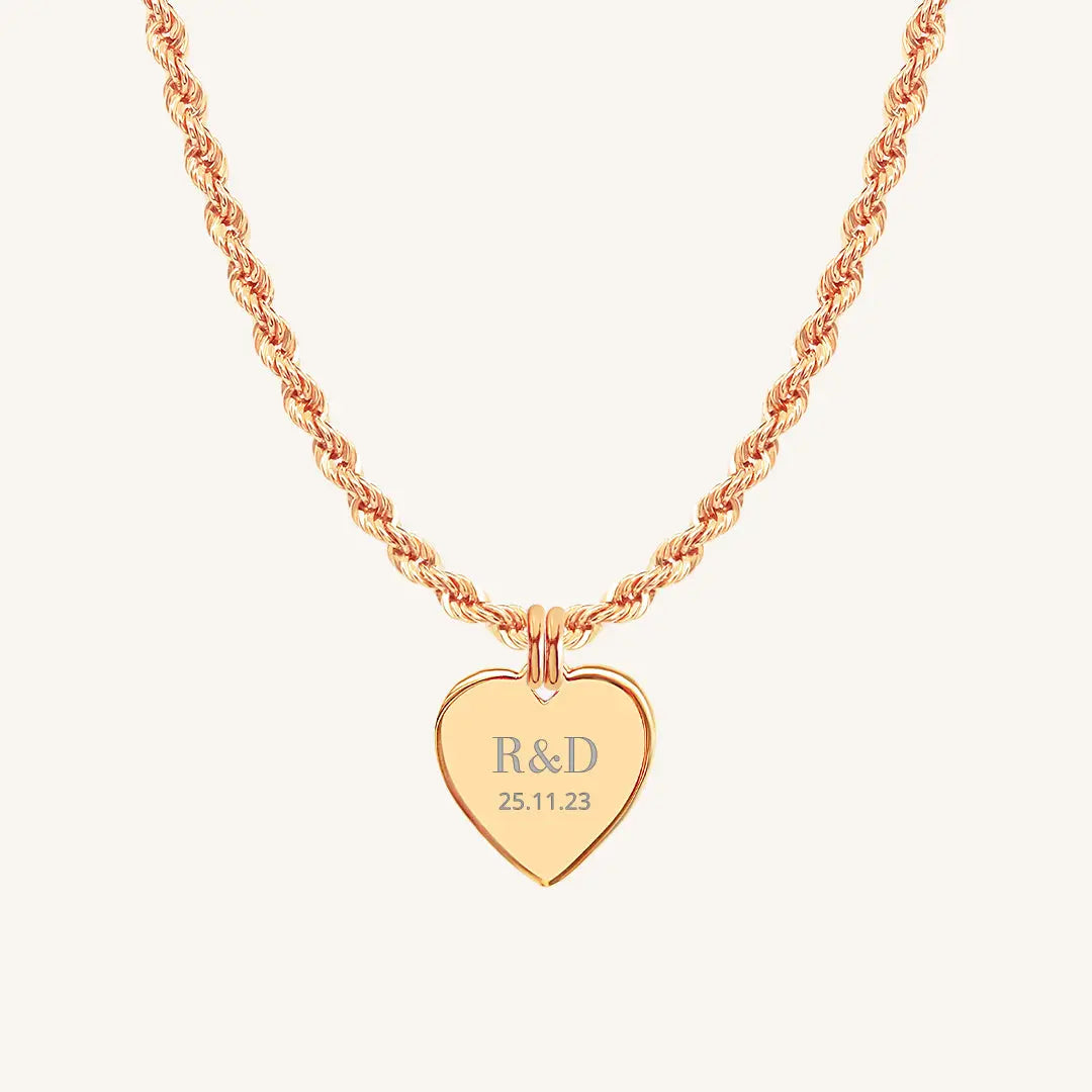 A rose heart-shaped necklace with a chain, featuring an engraved monogram initials and a date on the front.