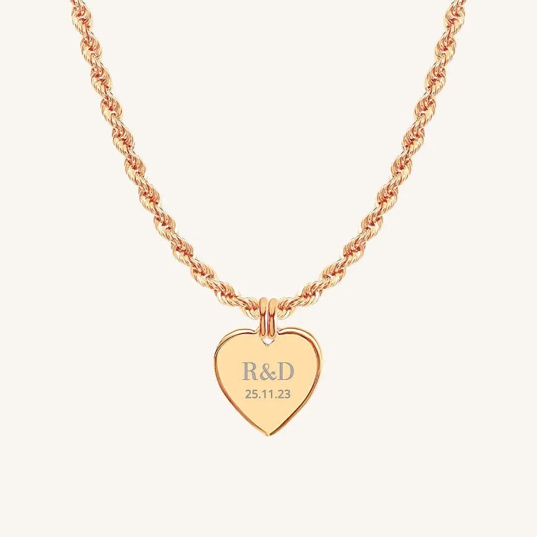 A rose heart-shaped necklace with a chain, featuring an engraved monogram initials and a date on the front.