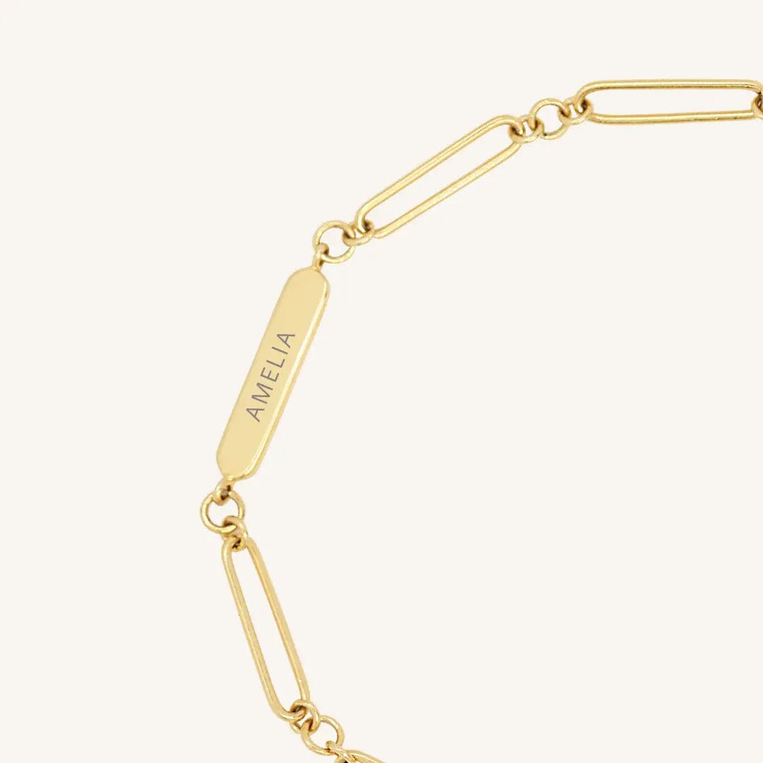 A gold chain bracelet with an adjustable fastening design and an engraveable panel.