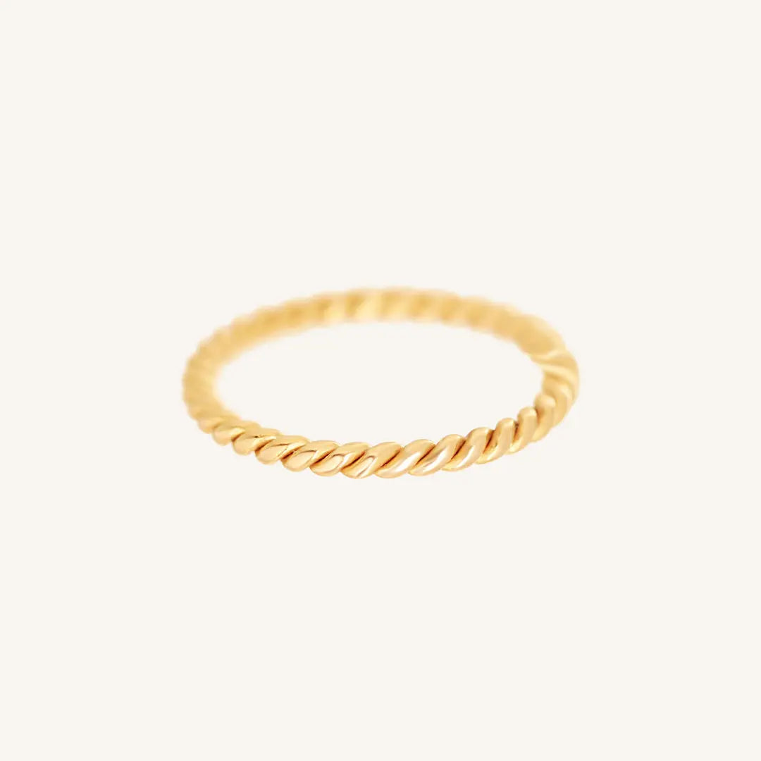 A gold-coloured stacking ring with a twisted design, displayed against a white background.