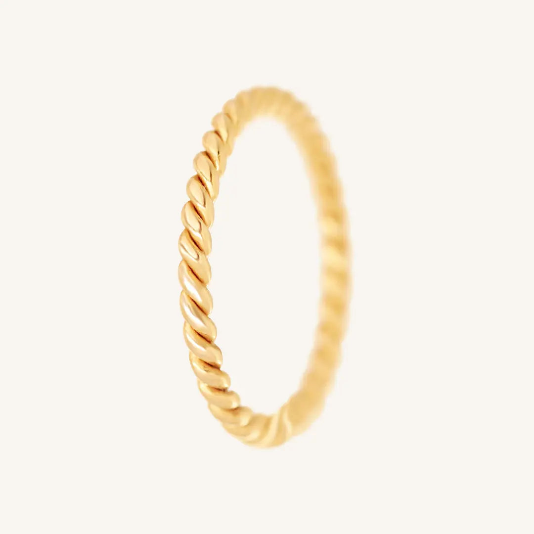 A gold-coloured stacking ring with a twisted design, displayed against a white background.