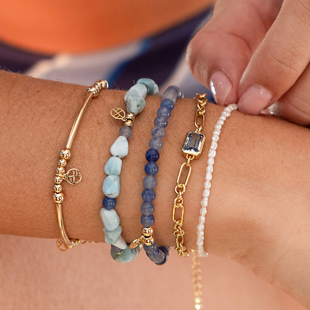Close-up of a wrist wearing multiple bracelets with a blurred background