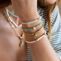 Bracelet with green beads and gold accents on a white background