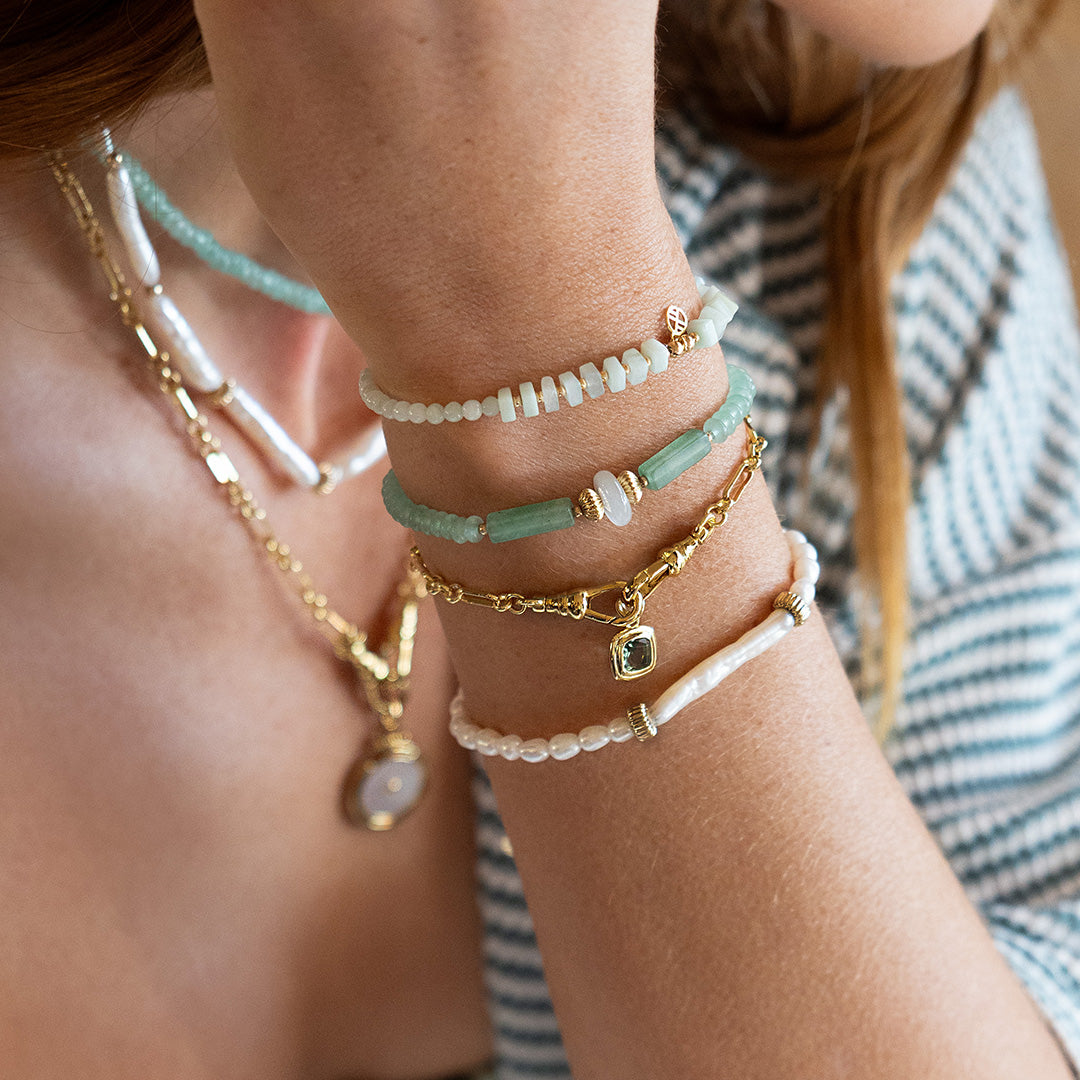 Close-up of a person's wrist wearing multiple bracelets with a blurred background