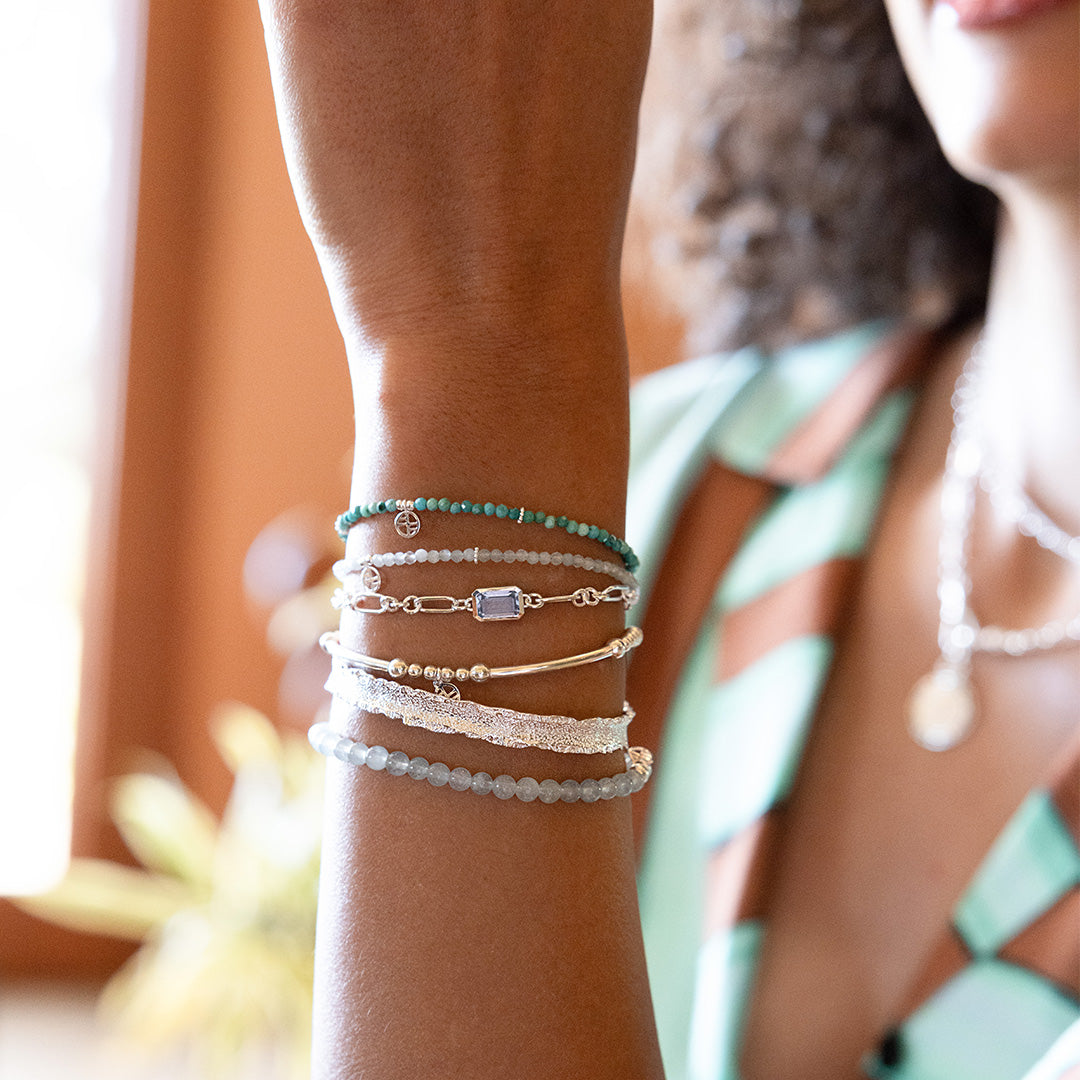 Close-up of a person's arm wearing multiple bracelets with a blurred background