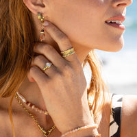 Pair of hoop charms with pink hue stones and gold accents on a white background