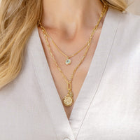 Silver pendant with a green gemstone on a white background