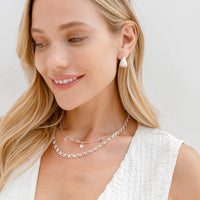 A pair of gold-colored chunky hoop earrings on a white background.