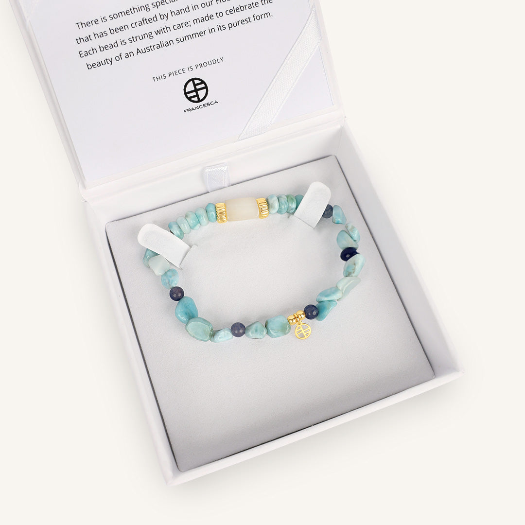 Beaded bracelet with blue and gold accents, displayed in white box