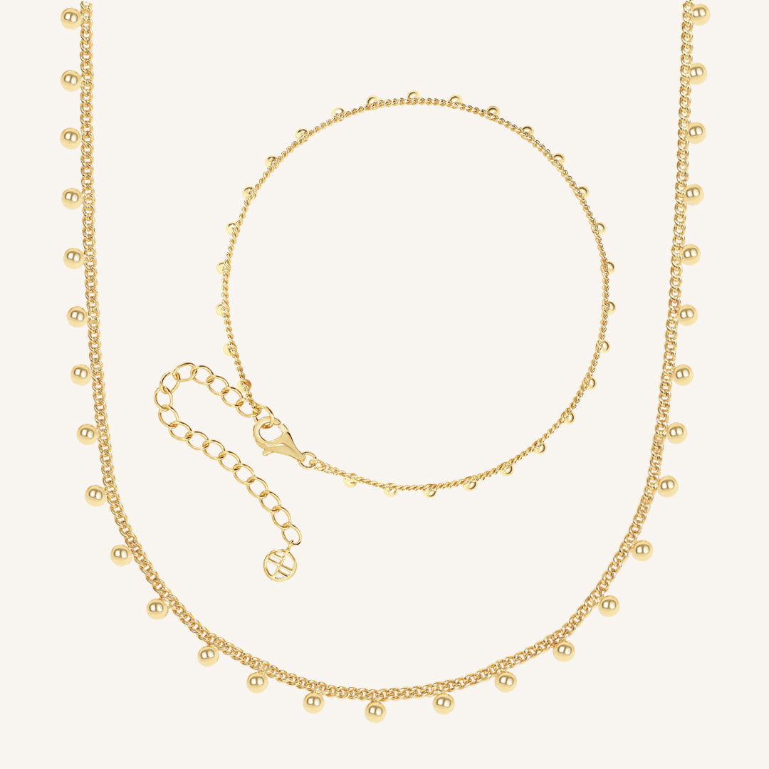 Gold necklace and bracelet set on a white background