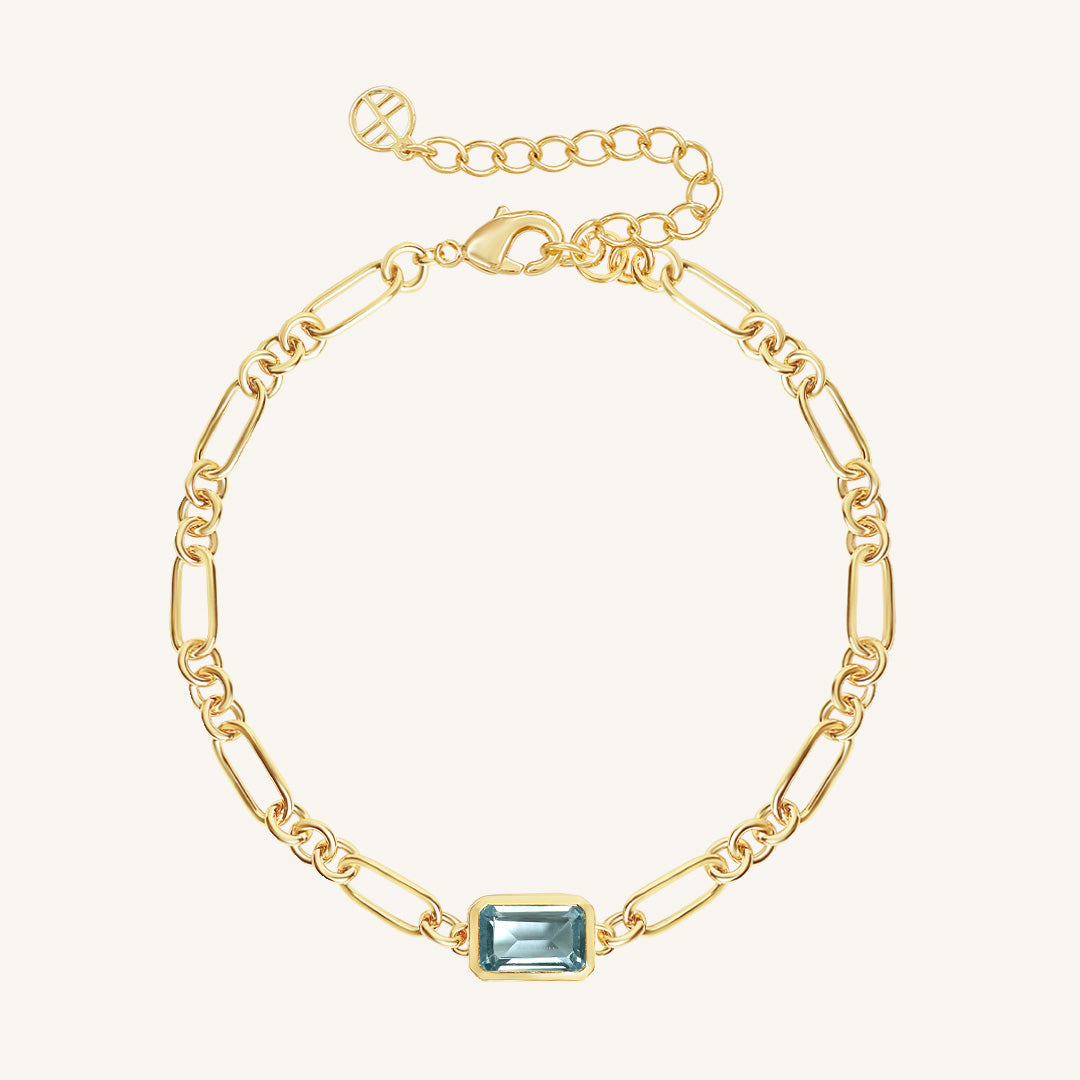 Gold bracelet with a blue gemstone on a white background