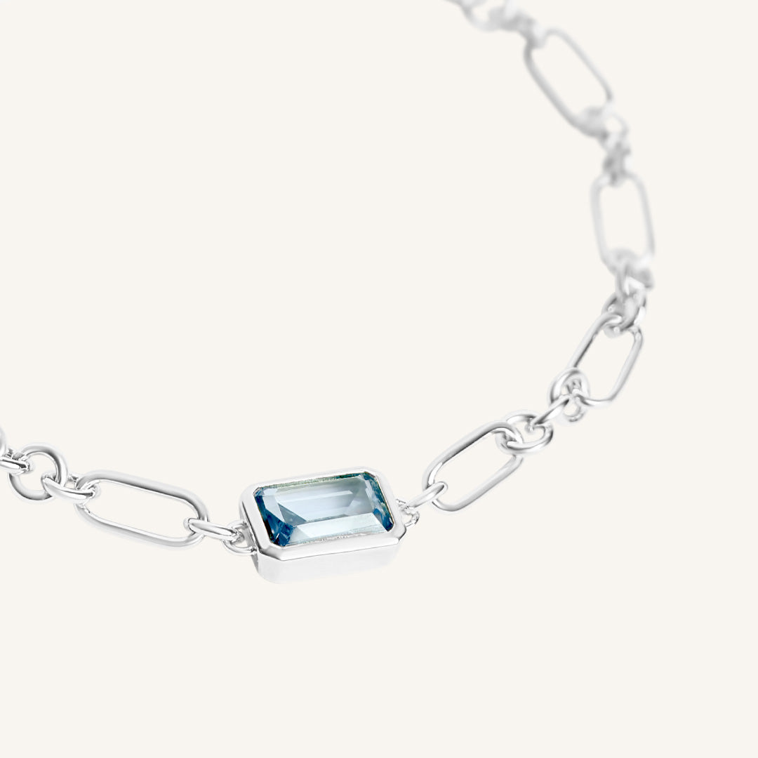 Silver bracelet with a blue gemstone on a white background