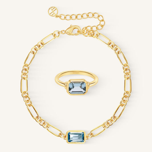 Gold bracelet and ring with blue gemstones on a white background