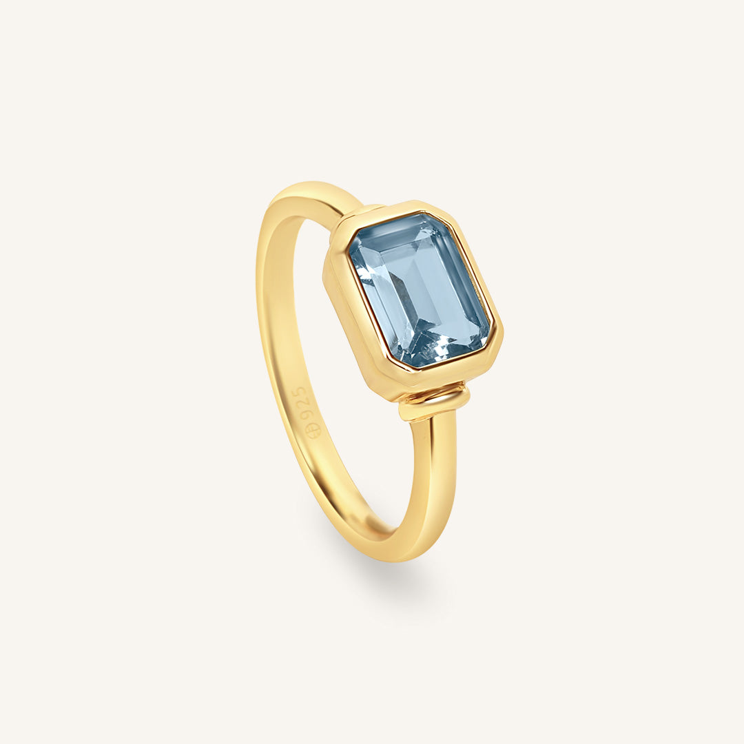 Gold ring with a blue gemstone on a white background