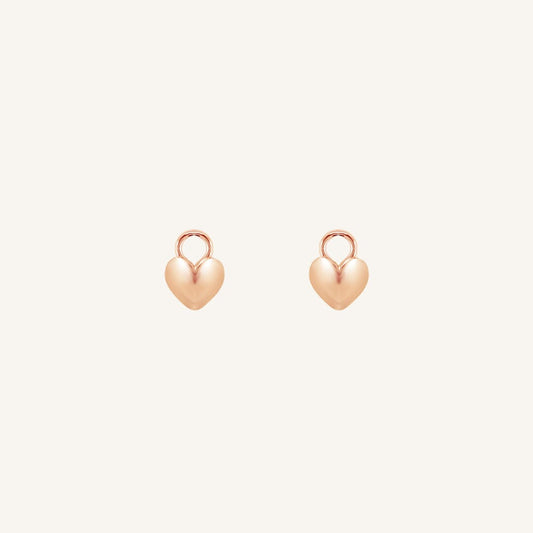 A pair of heart-shaped rose hoop charms against a white background