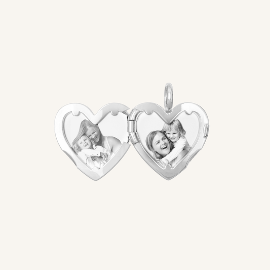 A silver heart-shaped photo locket with two images inside